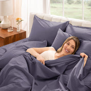 Woman putting bedding on a bed with GOTS Organic certification logo in the corner.