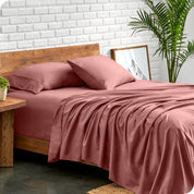 Microfiber sheets and matching pillowcases on a bed next to a large plant