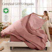 Woman putting bedding on a bed with GOTS Organic certification logo in the corner.