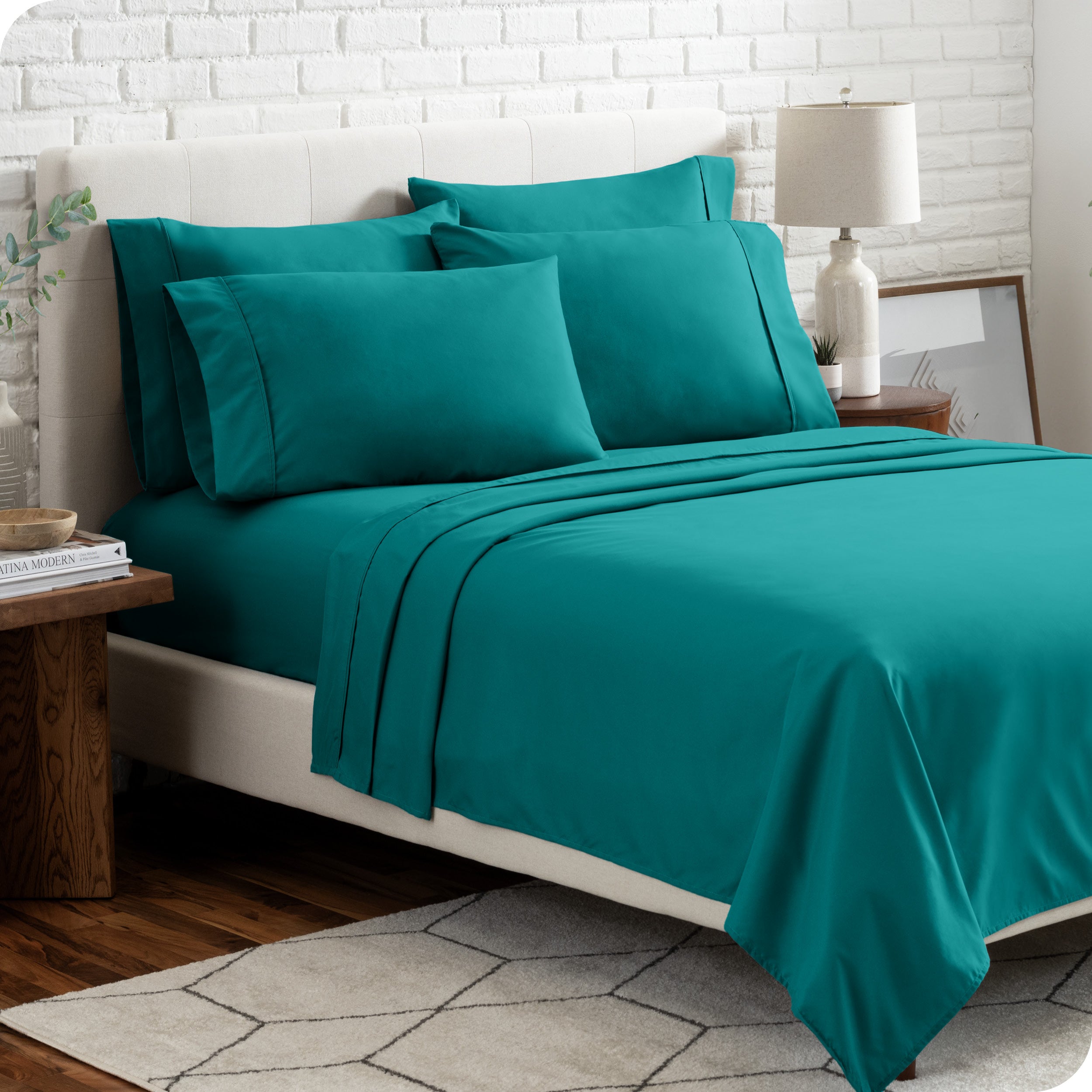 A bedroom setting with a bed made with the microfiber bed sheets and four pillows.
