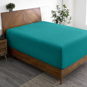 A wide corner view of a modern bed made with a microfiber fitted sheet on the mattress.