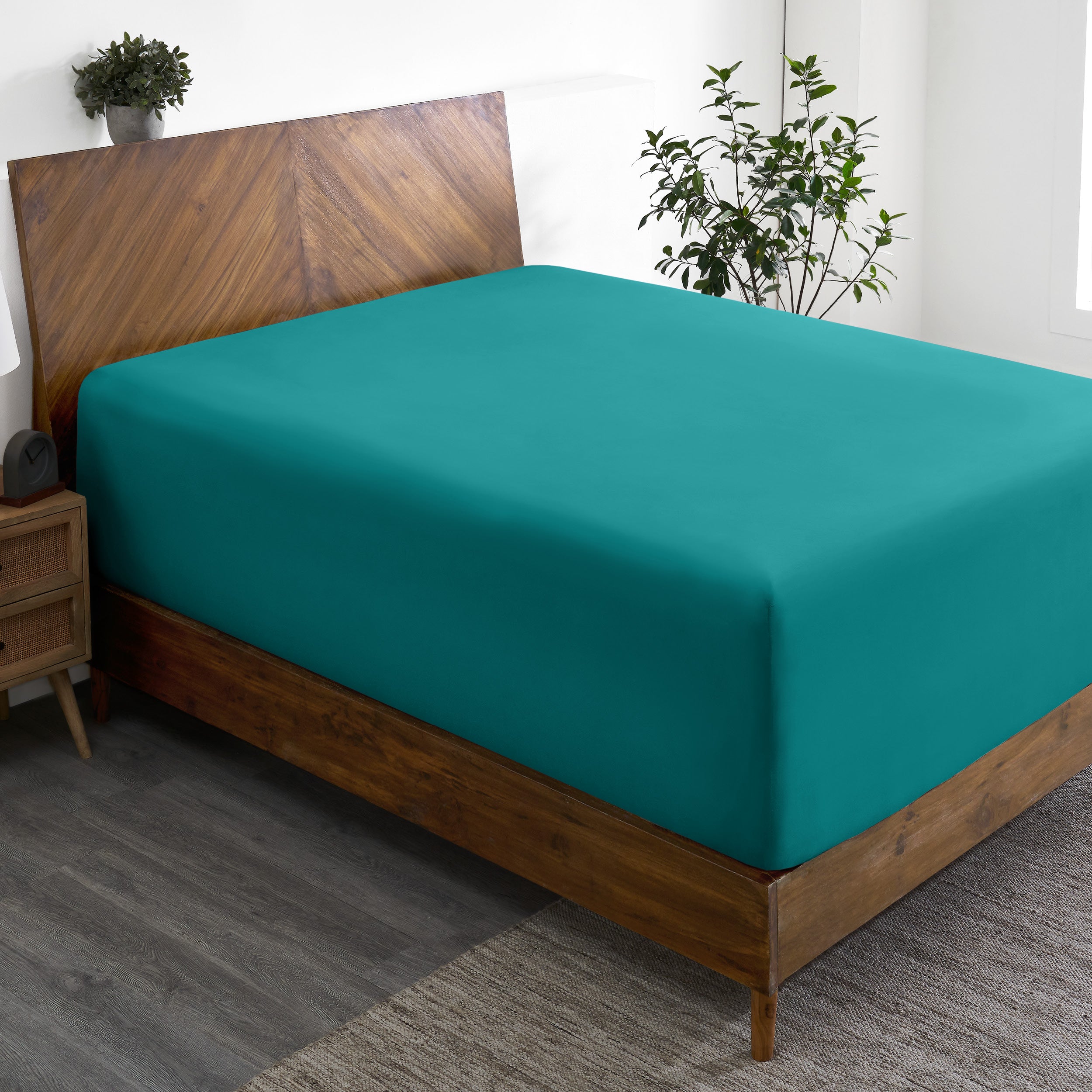 A wide corner view of a modern bed made with a microfiber fitted sheet on the mattress.