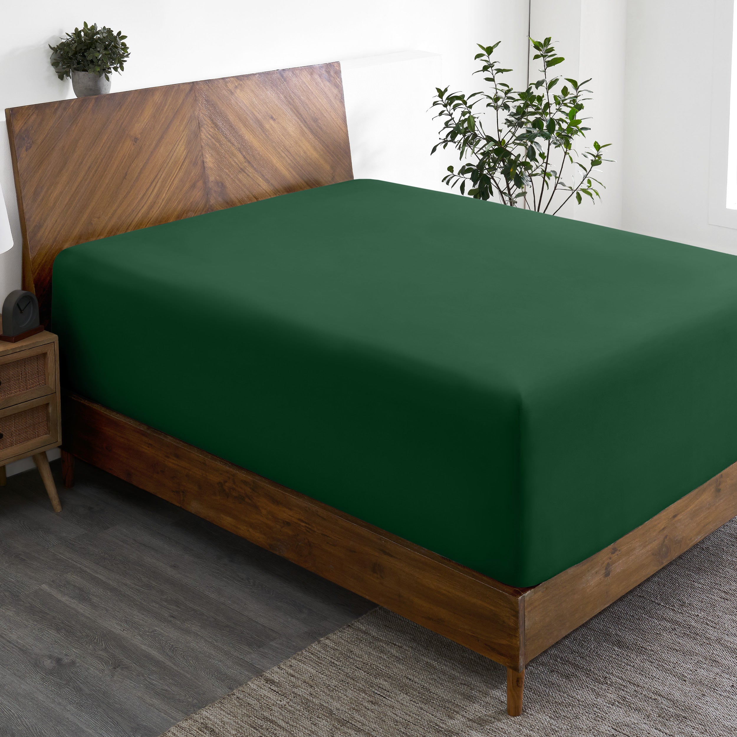 A wide corner view of a modern bed made with a microfiber fitted sheet on the mattress.