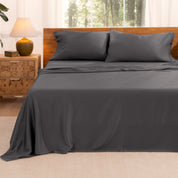 TENCEL™ sheet set on a bed with the flat sheet loosely draped over the top. The mattress is on a wooden bed frame.