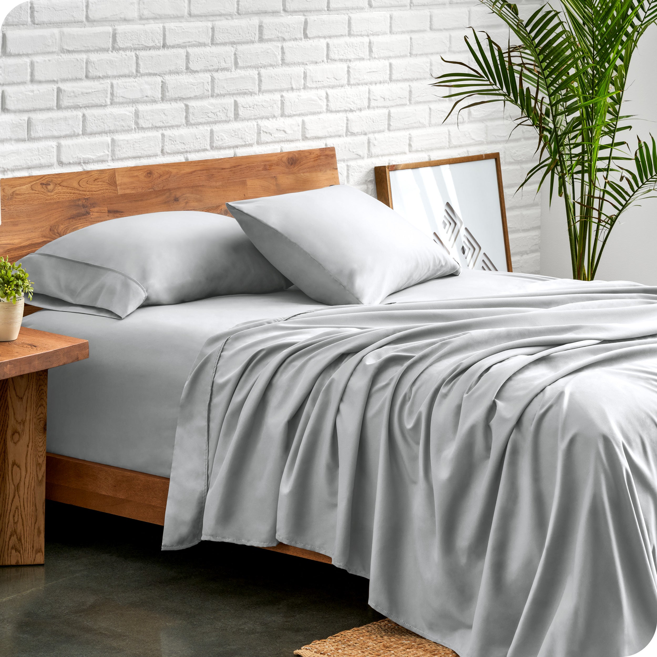 Microfiber sheets and matching pillowcases on a bed next to a large plant