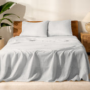 Bed with linen bedding and wooden headboard in a bedroom setting