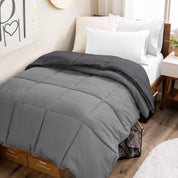 Wooden bed frame with a reversible comforter on the bed. The comforter is folded back over showing the two different colors.