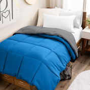 Wooden bed frame with a reversible comforter on the bed. The comforter is folded back over showing the two different colors.
