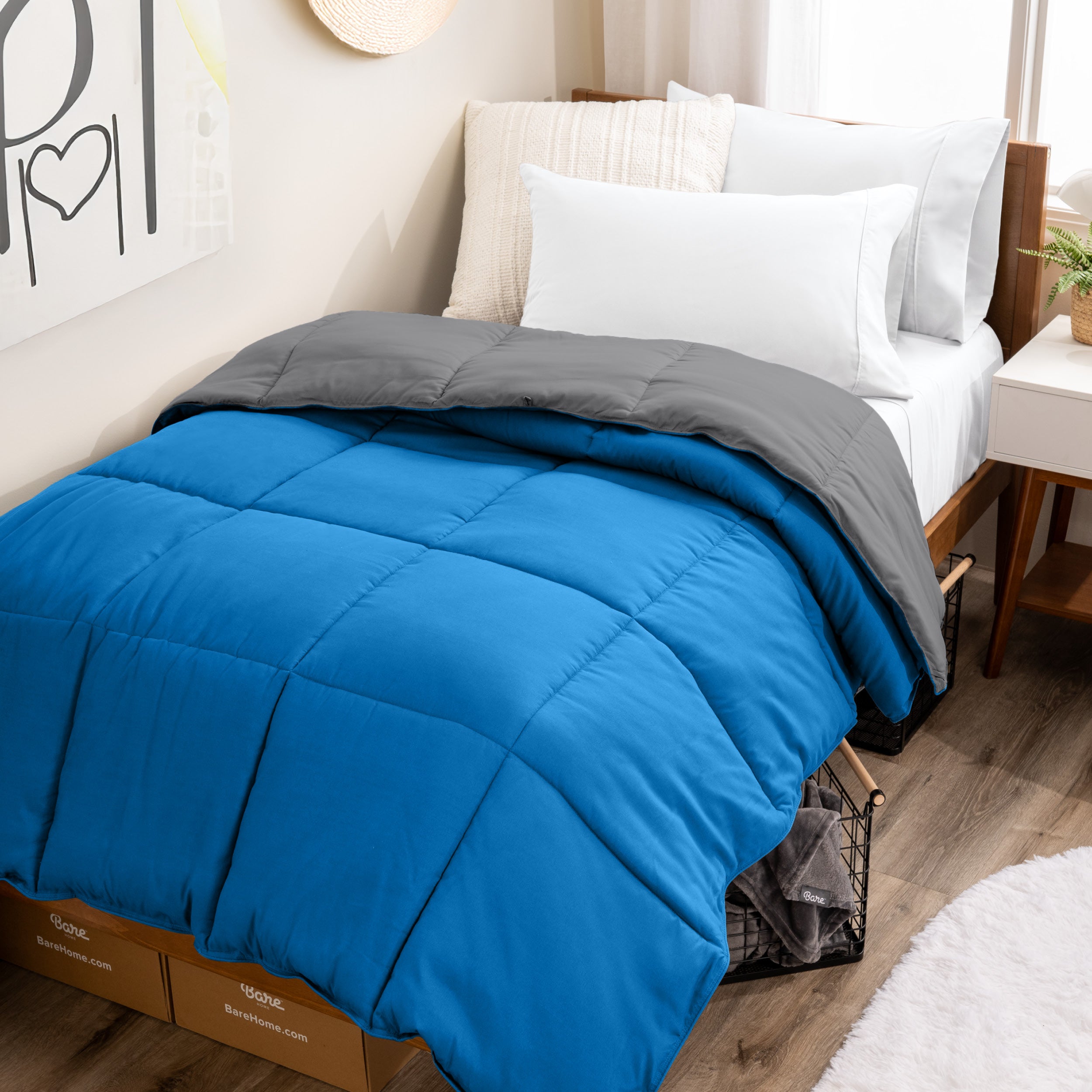 Wooden bed frame with a reversible comforter on the bed. The comforter is folded back over showing the two different colors.