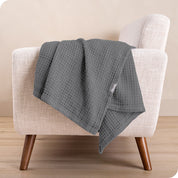 A cotton blanket on the arm of a chair
