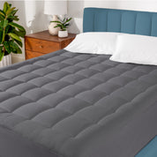 A mattress pad on a bed in a warm bright room.