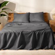 Bed with linen bedding and wooden headboard in a bedroom setting