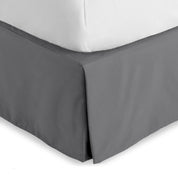 The corner of a bed skirt on a bed frame