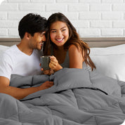 A couple sitting in bed with a comforter over them