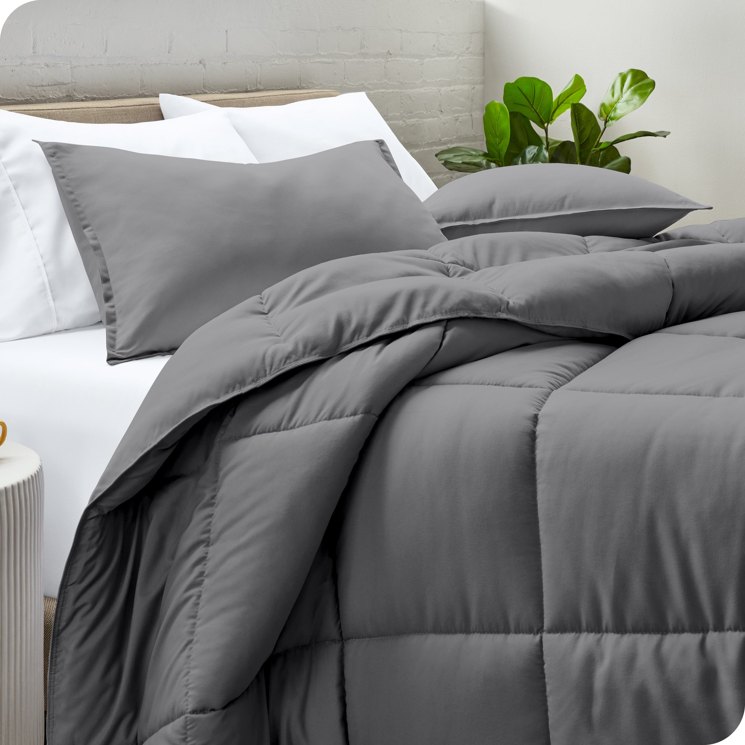 A side view of a modern bed with a comforter set and pillows on the bed