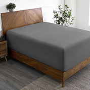 A wide corner view of a modern bed made with a microfiber fitted sheet on the mattress.