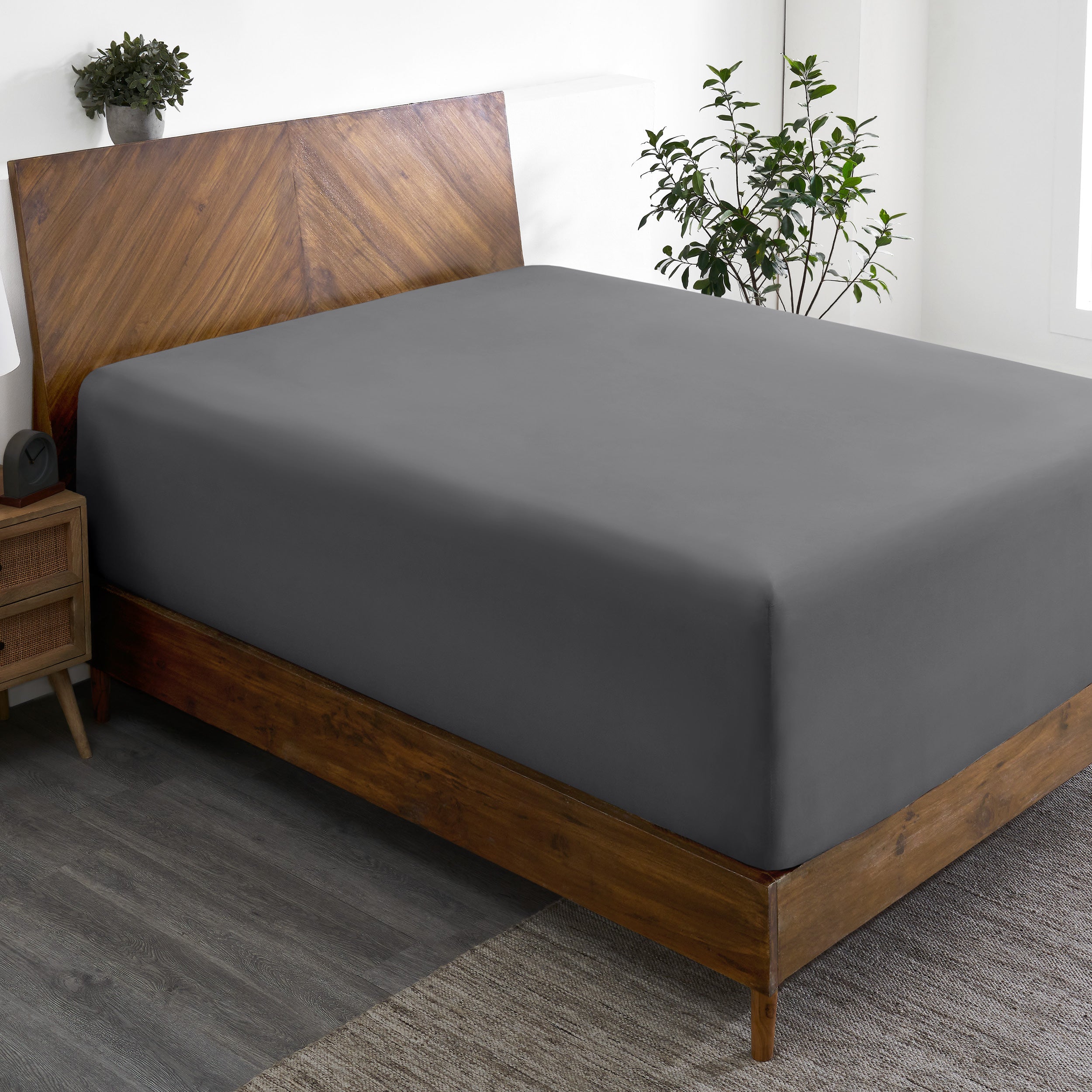 A wide corner view of a modern bed made with a microfiber fitted sheet on the mattress.