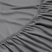 Close-up of a fitted sheet with elastic edge on a bed.