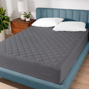 A modern bed with a quilted mattress pad on.
