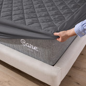 The corner of a mattress with a mattress pad putting on it