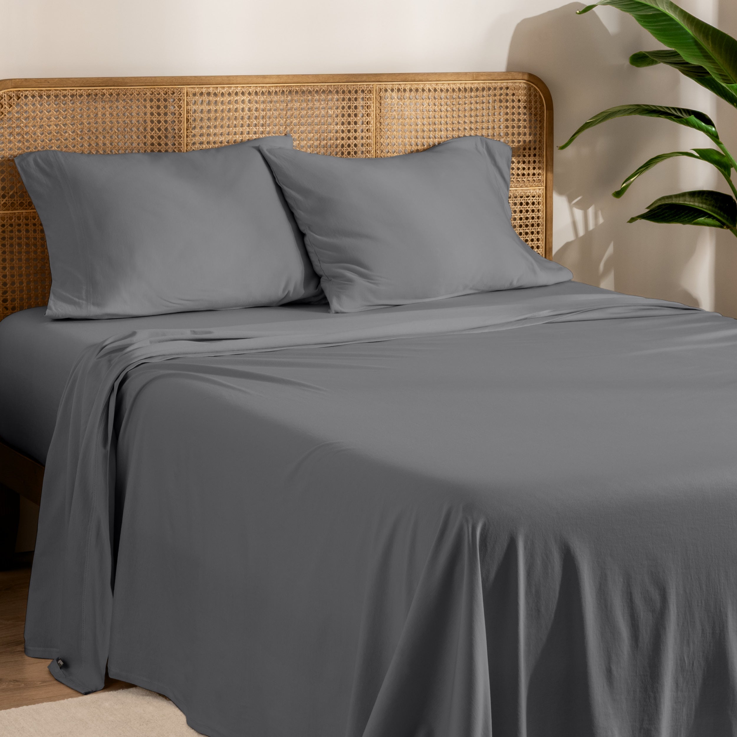 Organic jersey sheets and pillowcases on a bed with plants on the side in a bright and chill room scene.