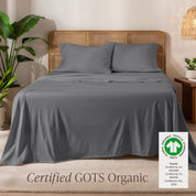 A bed in the middle of room with a set of Certified GOTS Organic Jersey Sheet Set on it.