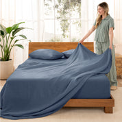 Woman arranging linen sheets on a wooden bed in a bright room with plants.
