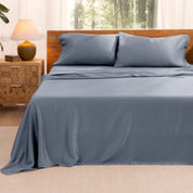 TENCEL™ sheet set on a bed with the flat sheet loosely draped over the top. The mattress is on a wooden bed frame.
