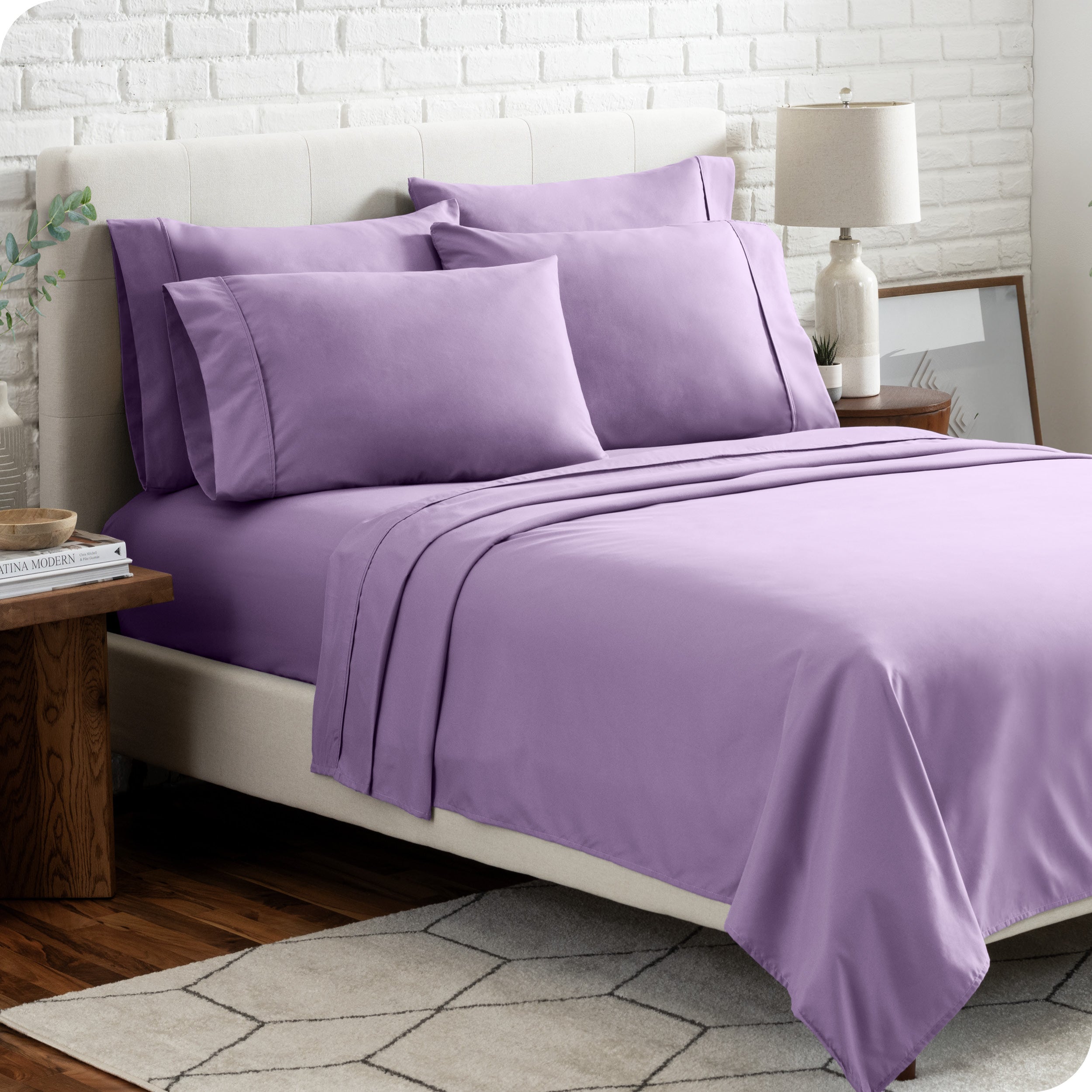 A bedroom setting with a bed made with the microfiber bed sheets and four pillows.