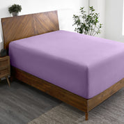 A wide corner view of a modern bed made with a microfiber fitted sheet on the mattress.