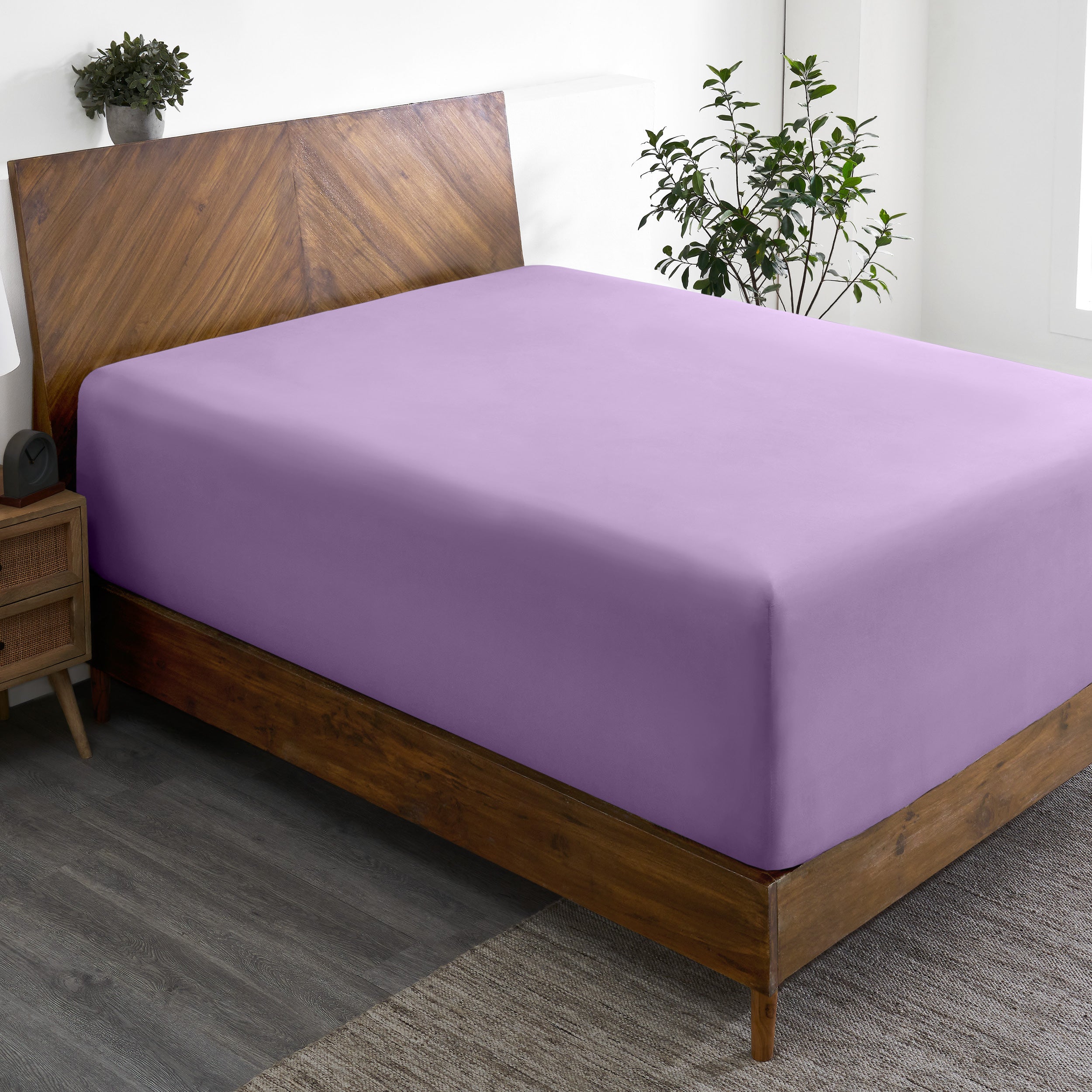 A wide corner view of a modern bed made with a microfiber fitted sheet on the mattress.
