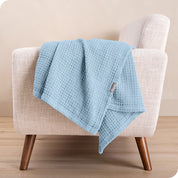 A cotton blanket on the arm of a chair