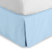 The corner of a bed skirt on a bed frame