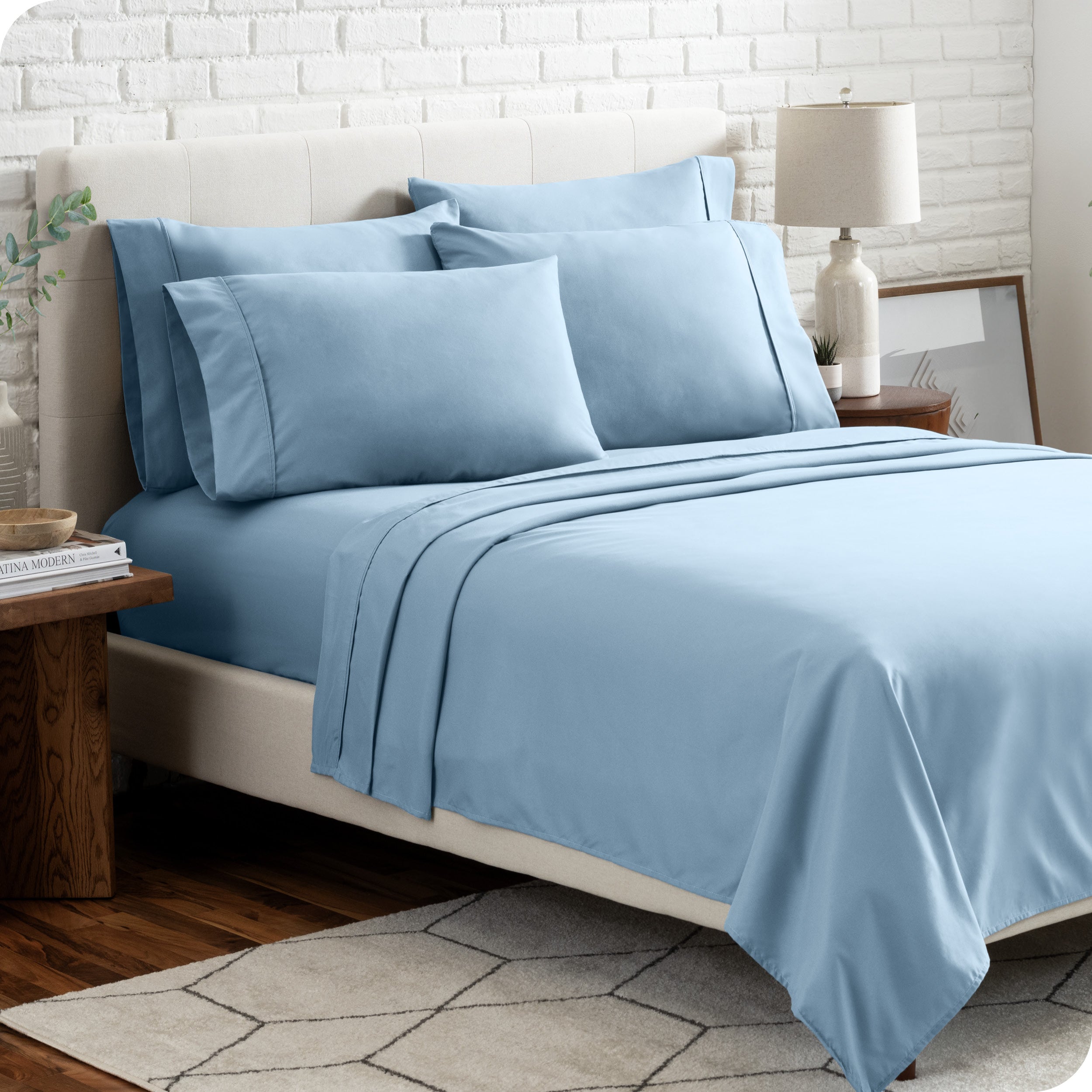 A bedroom setting with a bed made with the microfiber bed sheets and four pillows.