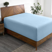 A wide corner view of a modern bed made with a microfiber fitted sheet on the mattress.