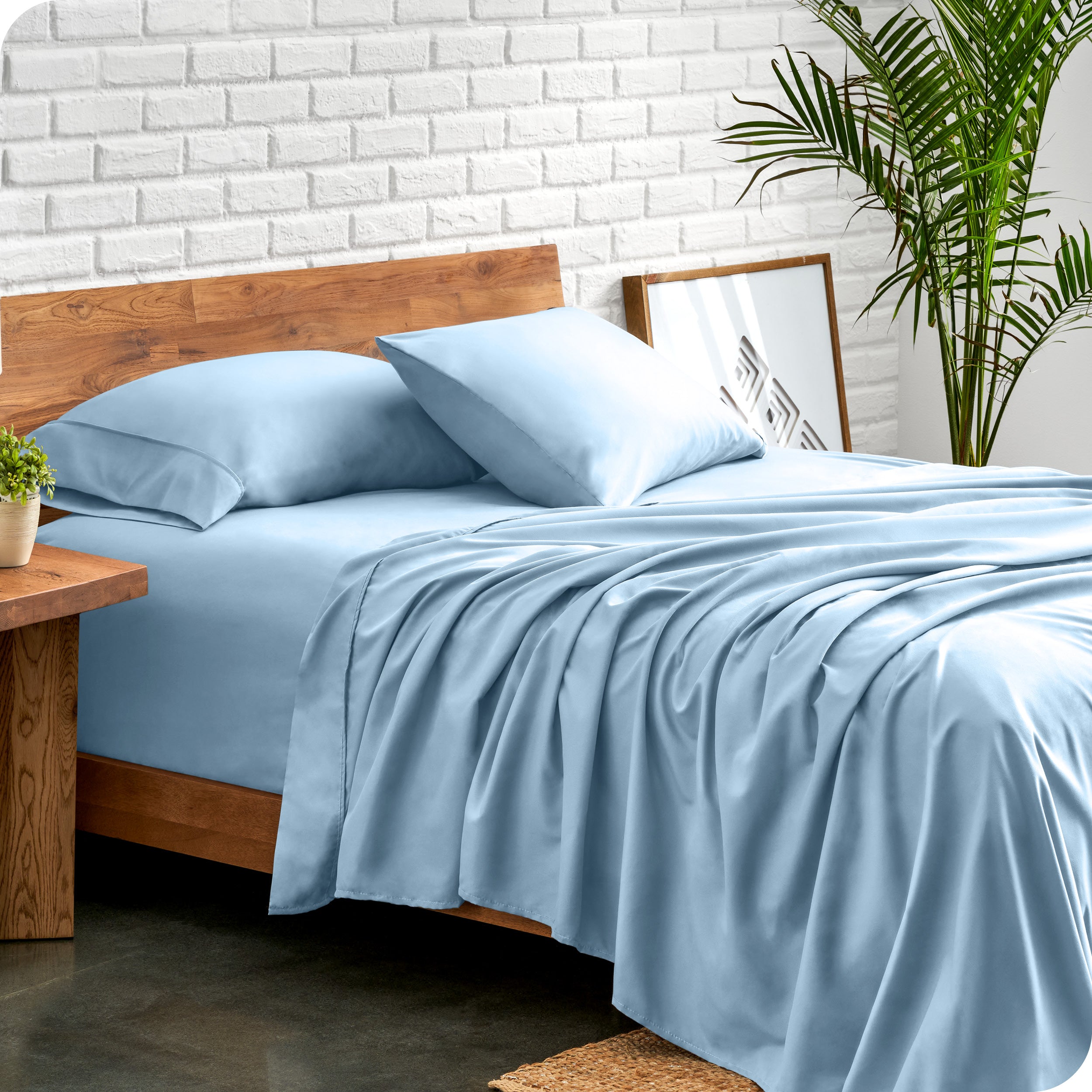 Microfiber sheets and matching pillowcases on a bed next to a large plant