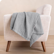 A cotton blanket on the arm of a chair