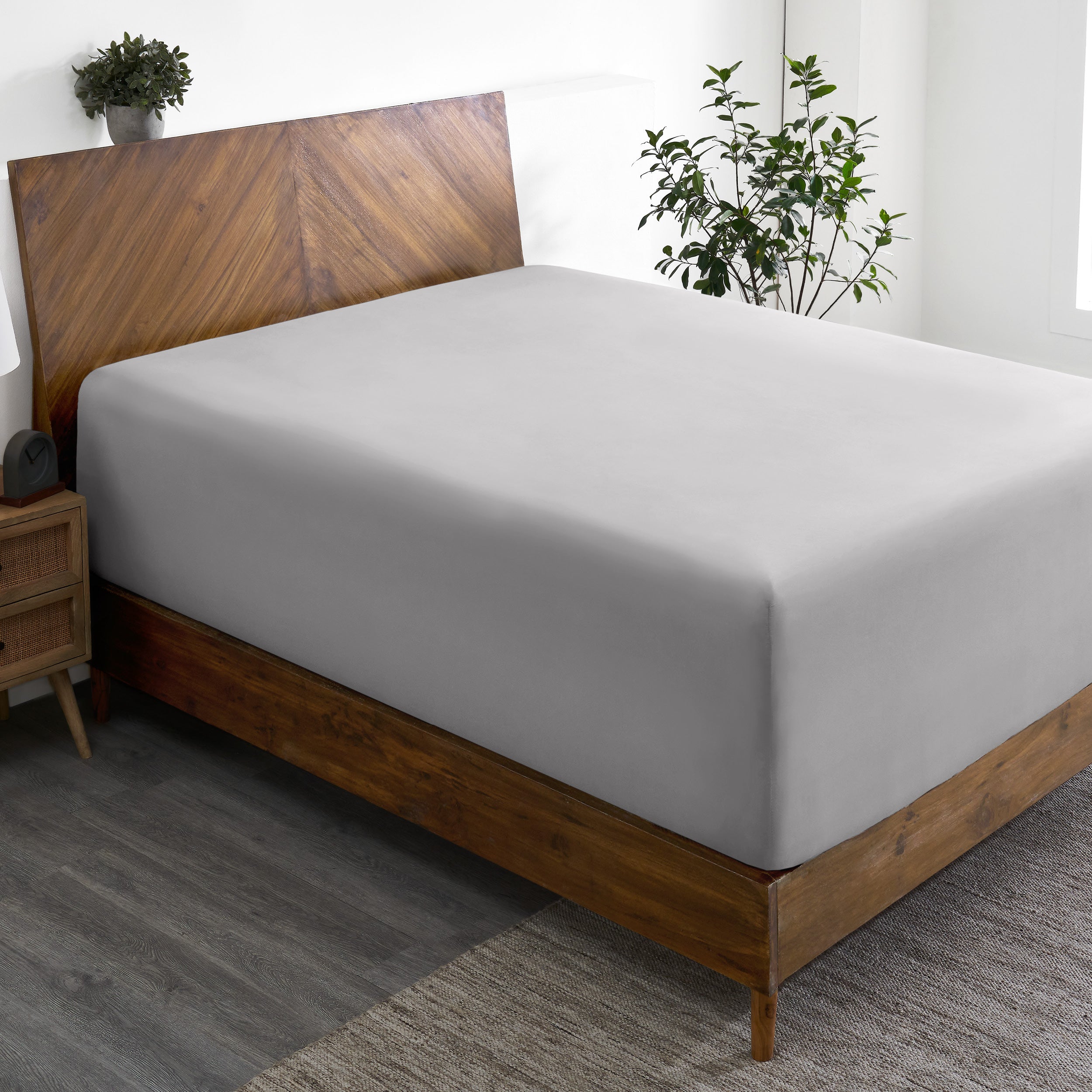 A wide corner view of a modern bed made with a microfiber fitted sheet on the mattress.