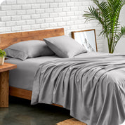 Microfiber sheets and matching pillowcases on a bed next to a large plant