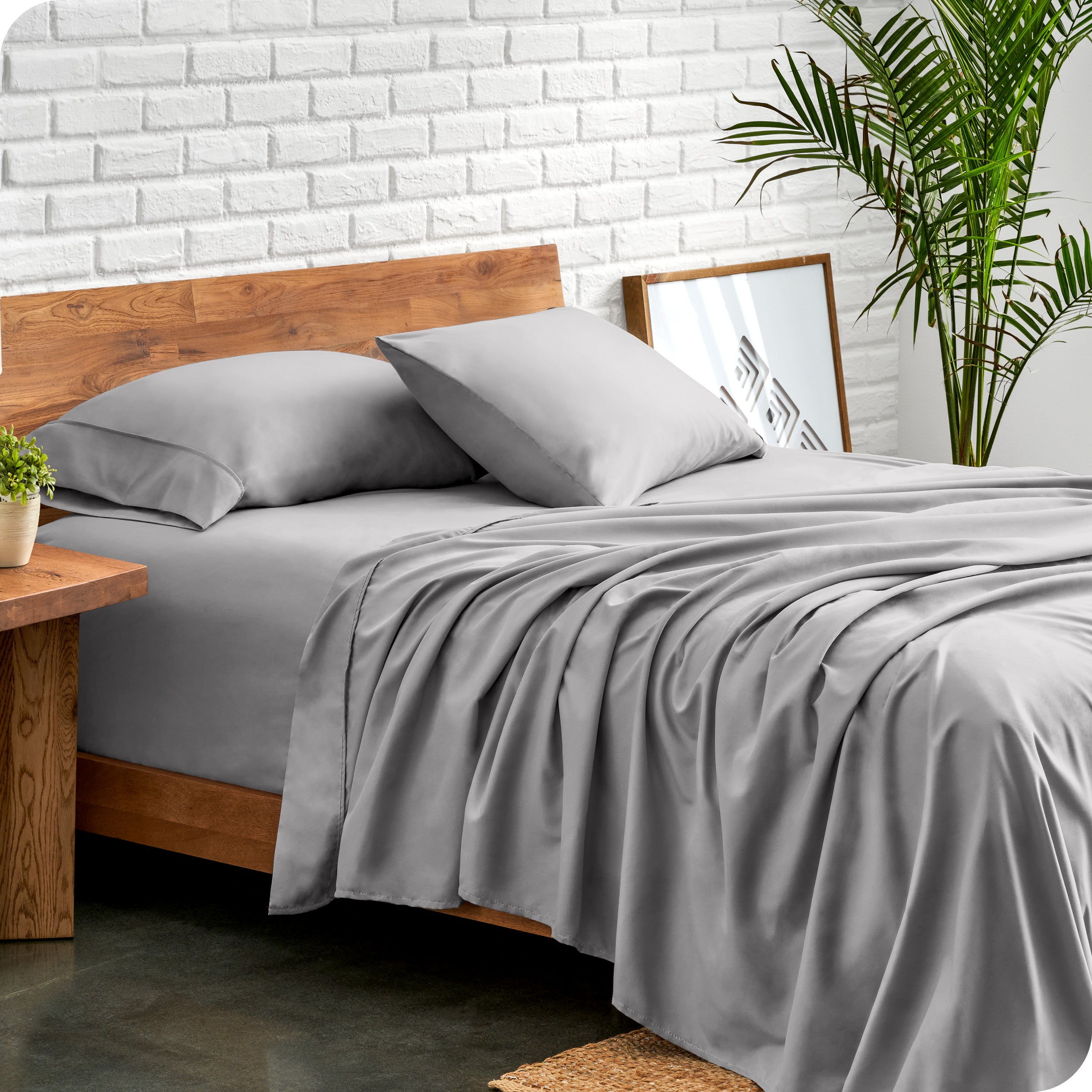 Microfiber sheets and matching pillowcases on a bed next to a large plant