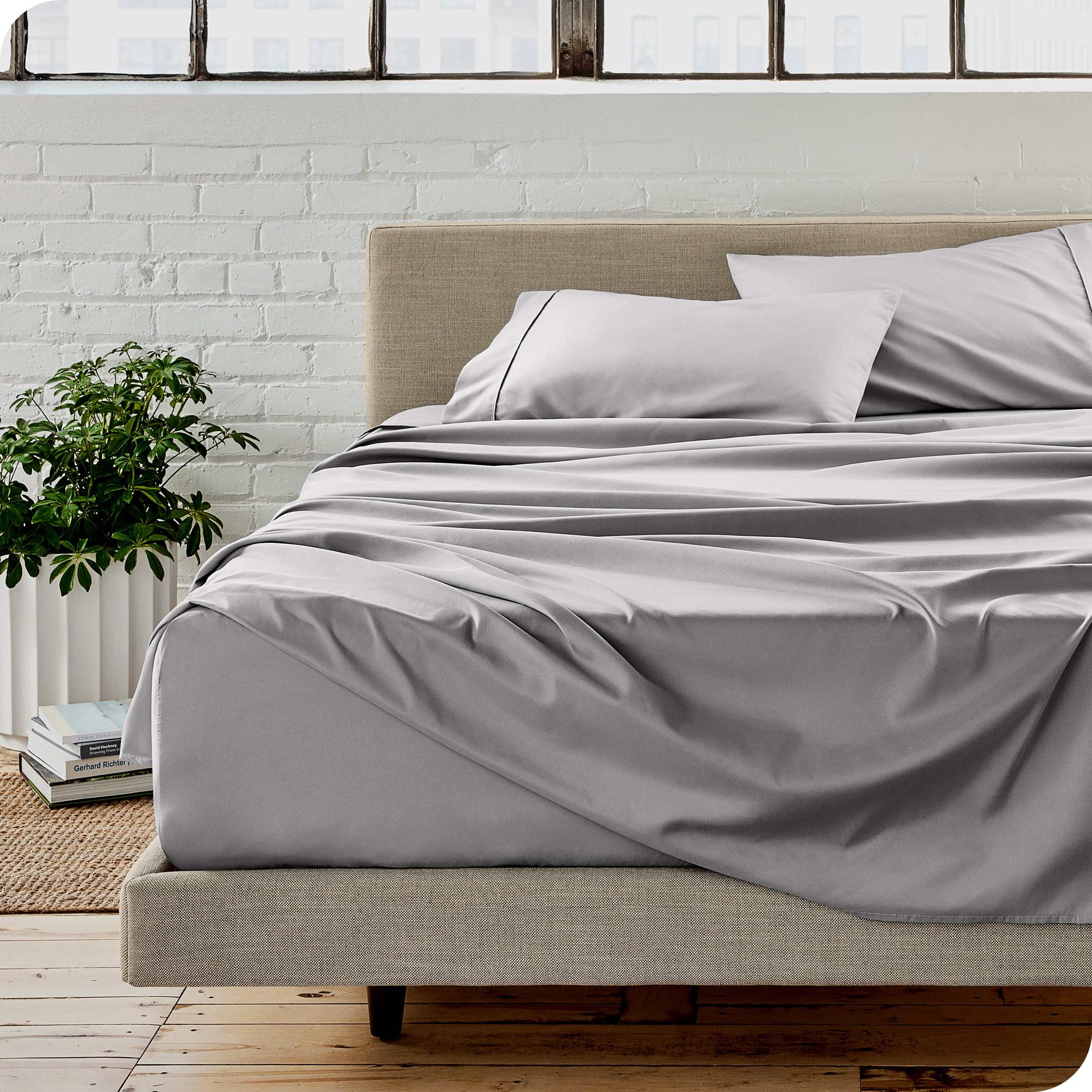 Microfiber sheets on a bed with a brick wall behind it