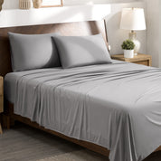 Stretch sheets on a bed with a wooden headboard in a bedroom setting.