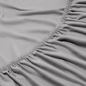 Close-up of a fitted sheet with elastic edge on a bed.