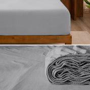 A divided image showing both the corner of a bed with organic jersey sheet and the folded sheet stacked on the bed.