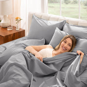 Woman lying in bed under percale sheets with a bright room setting