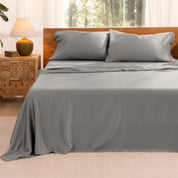TENCEL™ sheet set on a bed with the flat sheet loosely draped over the top. The mattress is on a wooden bed frame.