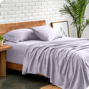 Microfiber sheets and matching pillowcases on a bed next to a large plant