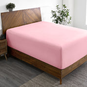 A wide corner view of a modern bed made with a microfiber fitted sheet on the mattress.
