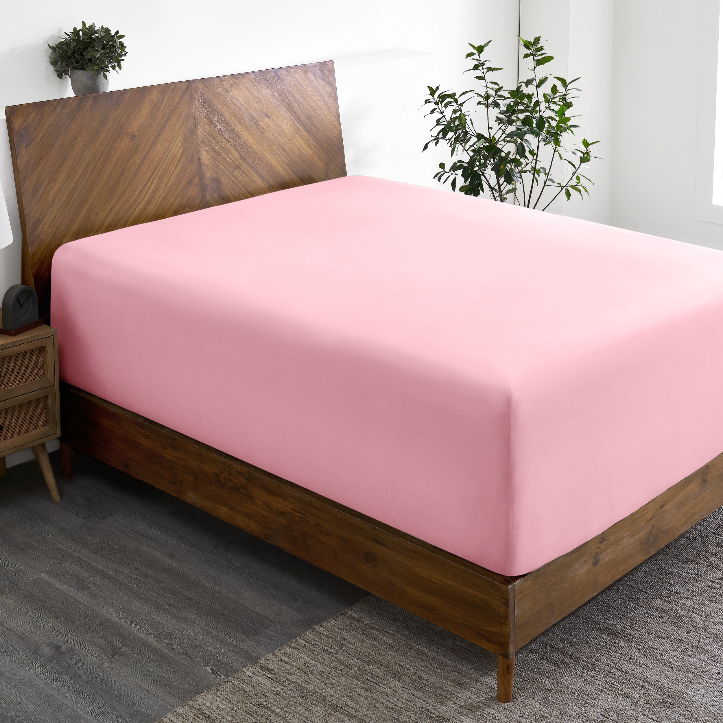 A wide corner view of a modern bed made with a microfiber fitted sheet on the mattress.