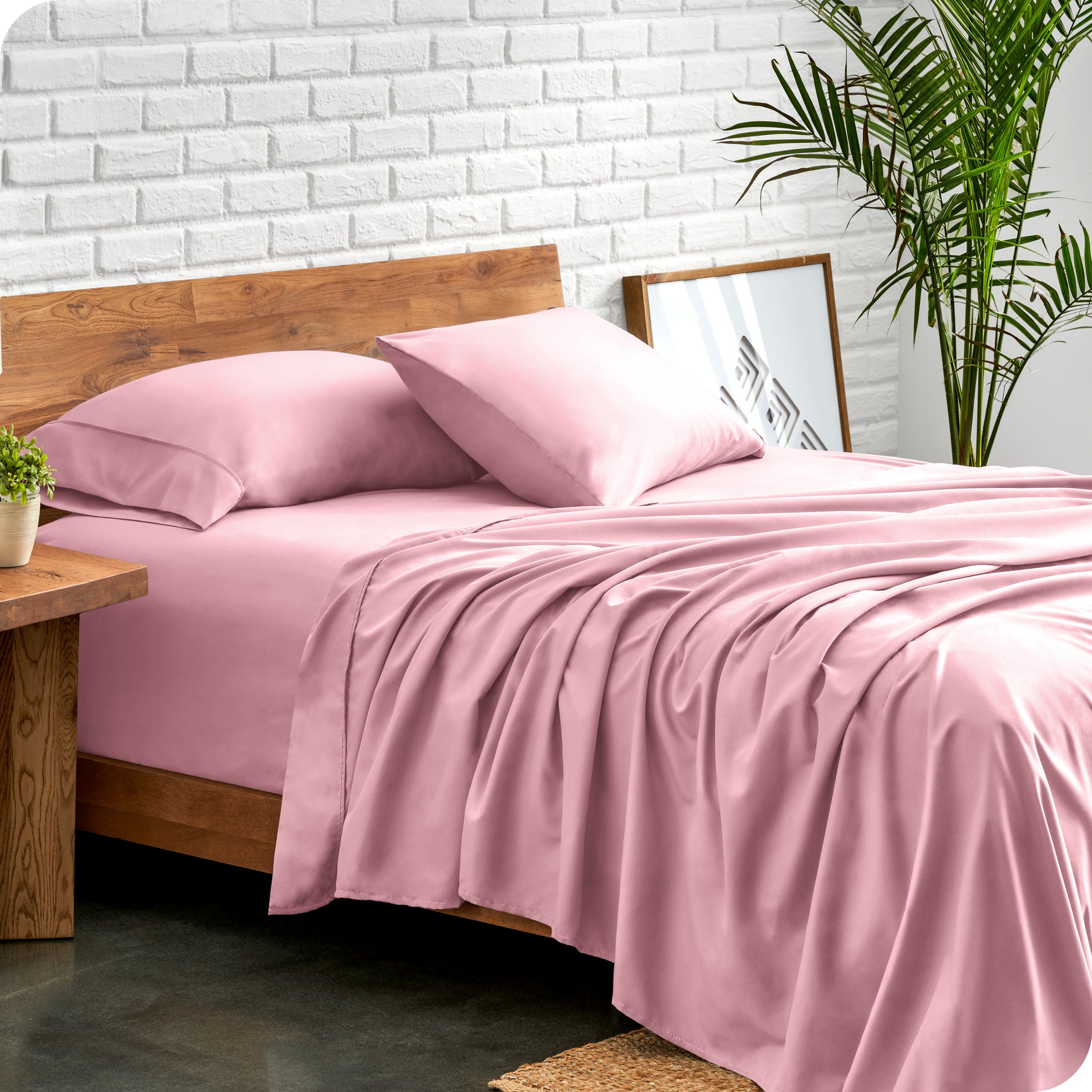 Microfiber sheets and matching pillowcases on a bed next to a large plant